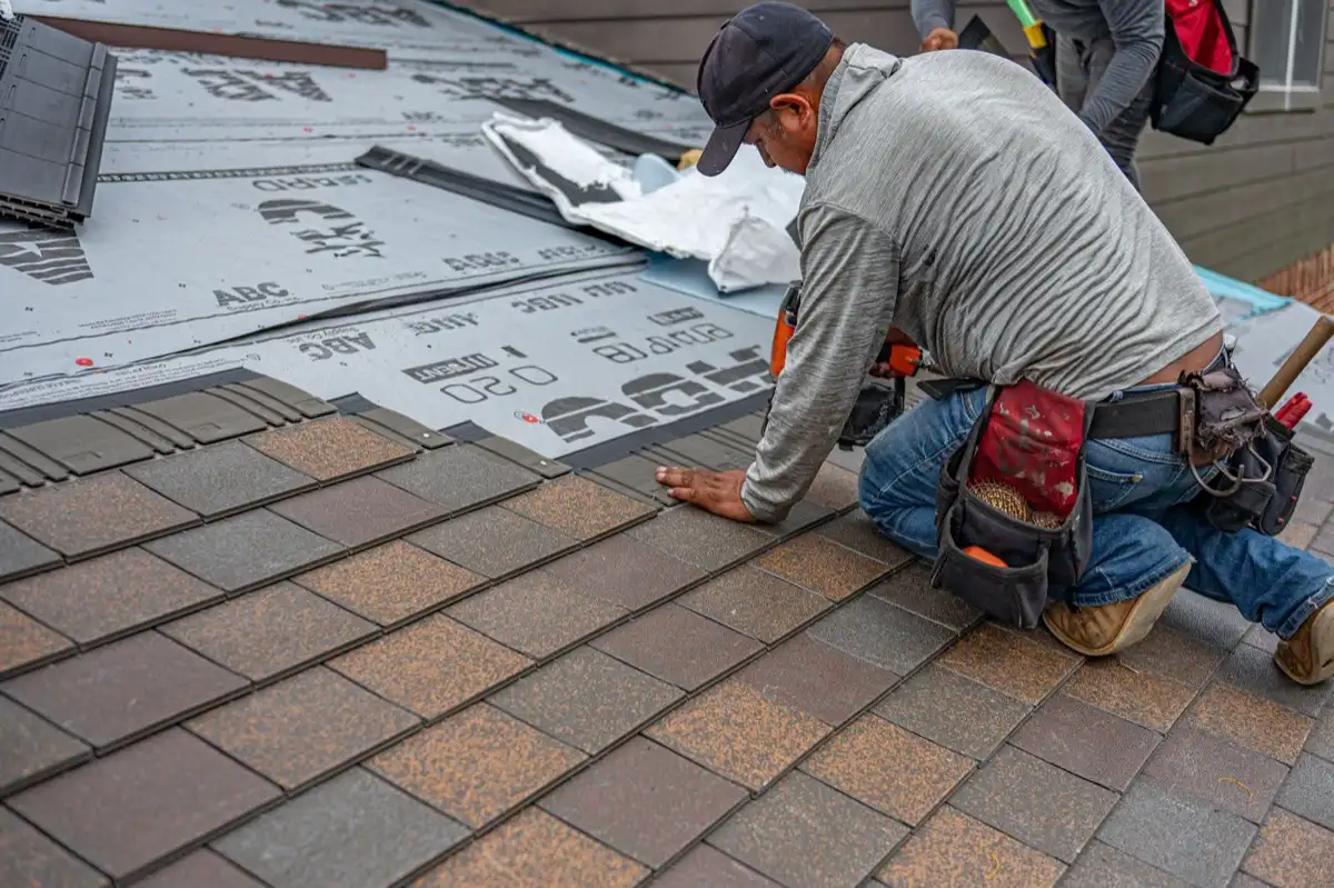 Roofing installer fastening shingles over new underlayment in San Angelo, TX